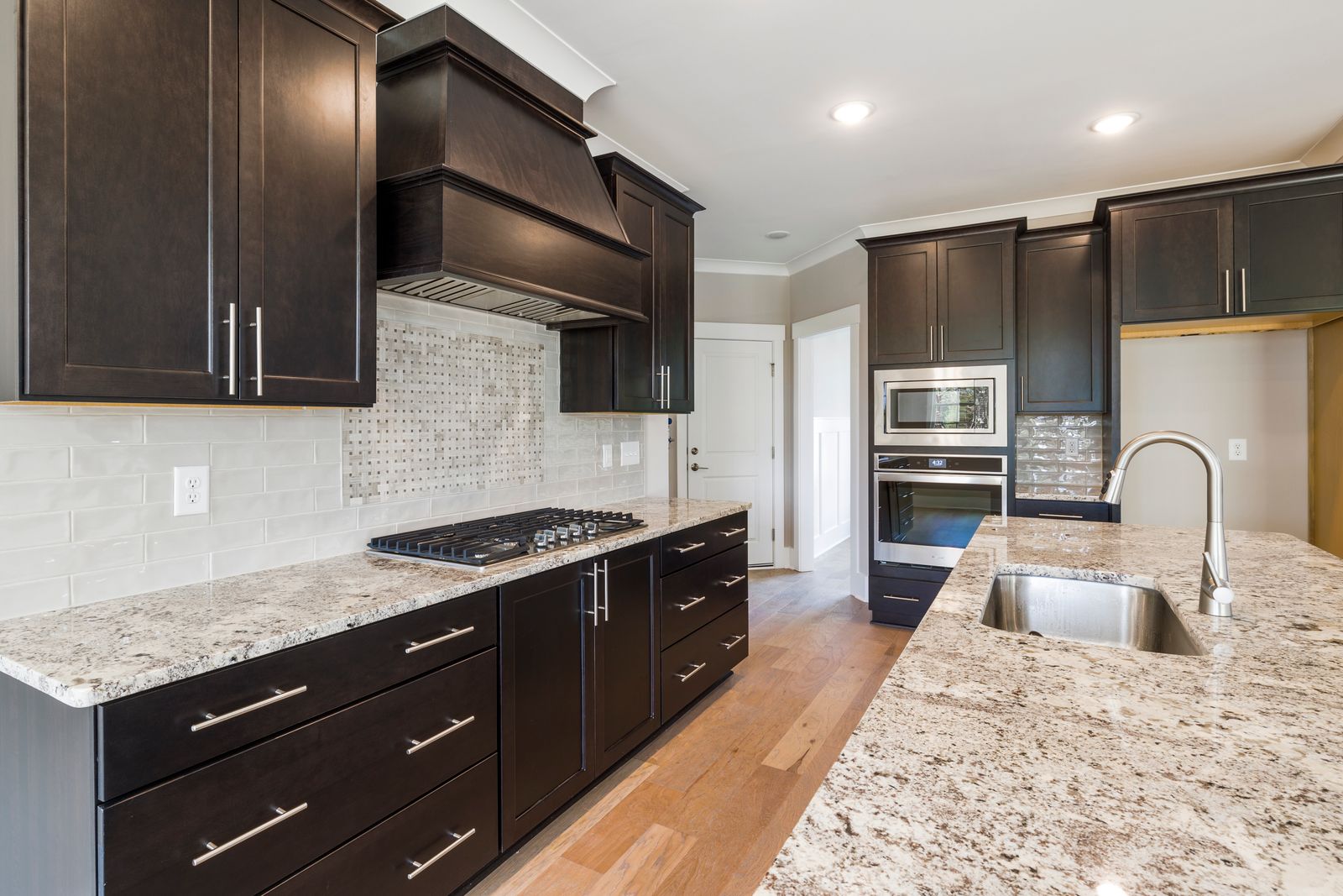 Contemporary kitchen with dark custom cabinetry and granite countertops