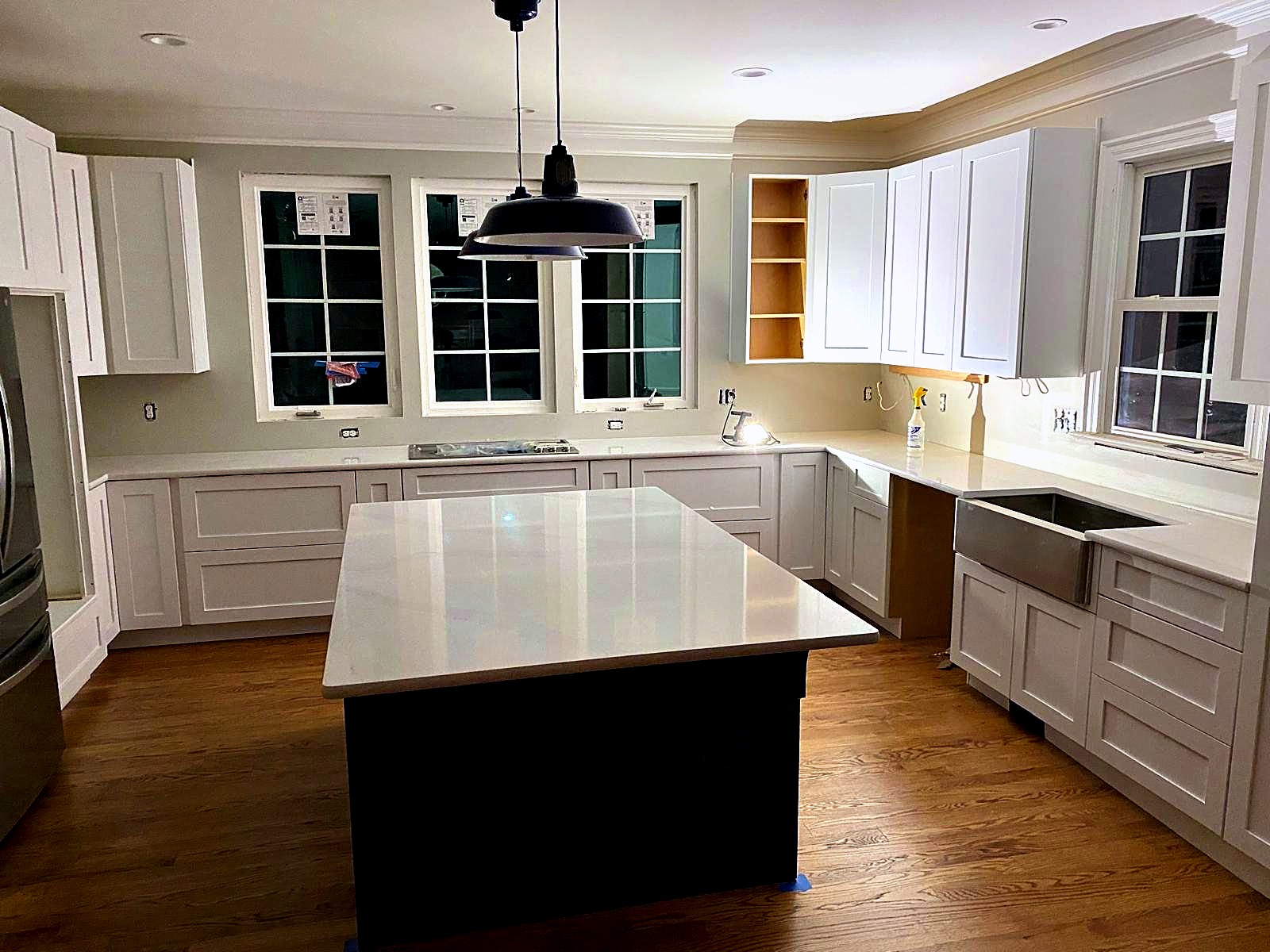 Custom white kitchen cabinetry with a quartz island, built by Stone Forever