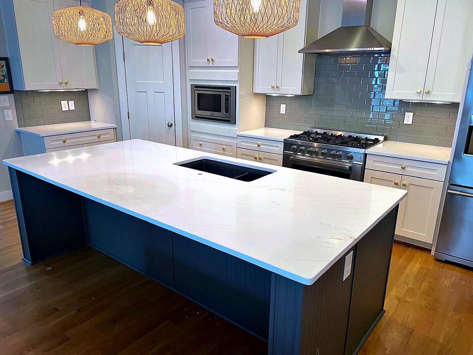 White quartz waterfall island kitchen with pendant lighting, installed by Stone Forever